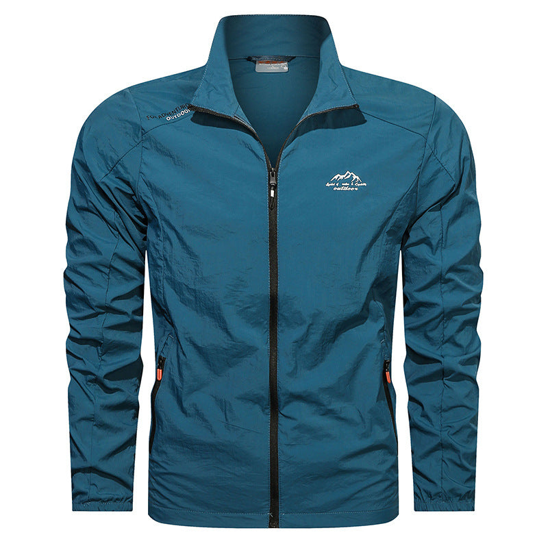 Giacca a vento blu da uomo con zip frontale, colletto alto e logo montagna. Ideale per escursionismo e attività outdoor. Tessuto leggero e resistente.