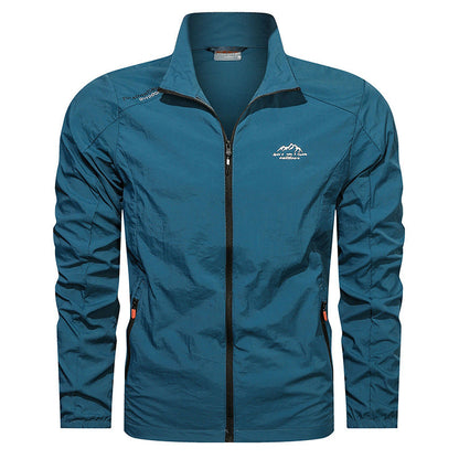 Giacca a vento blu da uomo con zip frontale, colletto alto e logo montagna. Ideale per escursionismo e attività outdoor. Tessuto leggero e resistente.
