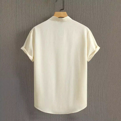 Camicia bianca a maniche corte in lino, vista posteriore, appesa su gruccia. Design minimalista, ideale per look estivi casual ed eleganti.