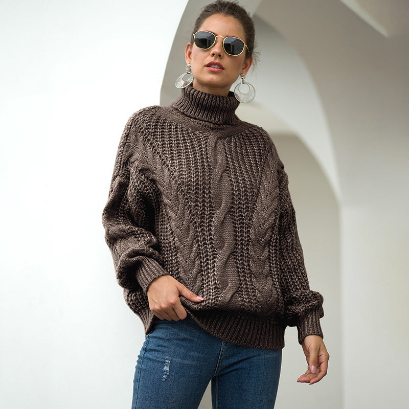 Donna con occhiali da sole indossa maglione marrone a collo alto e jeans, posa davanti a un arco bianco. Moda autunnale, stile casual chic.