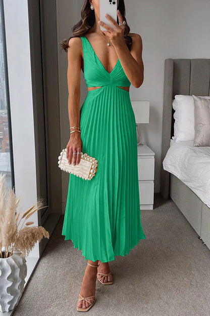Donna in abito verde plissettato con scollo a V, borsa bianca con perle, sandali beige, in camera moderna. Moda elegante, abbigliamento estivo.