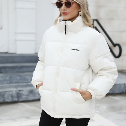 Donna con giacca invernale bianca, occhiali da sole e orecchini, su sfondo urbano. Moda invernale, abbigliamento caldo, stile casual chic.
