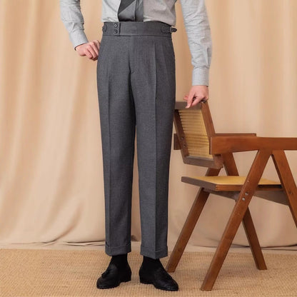 Pantaloni eleganti grigi da uomo, abbinati a camicia chiara e scarpe nere, accanto a sedia in legno. Moda maschile classica e sofisticata.