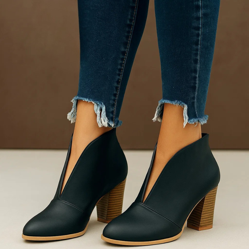 Stivaletti neri con tacco largo in legno, indossati con jeans strappati alla caviglia. Moda autunnale, calzature eleganti donna.