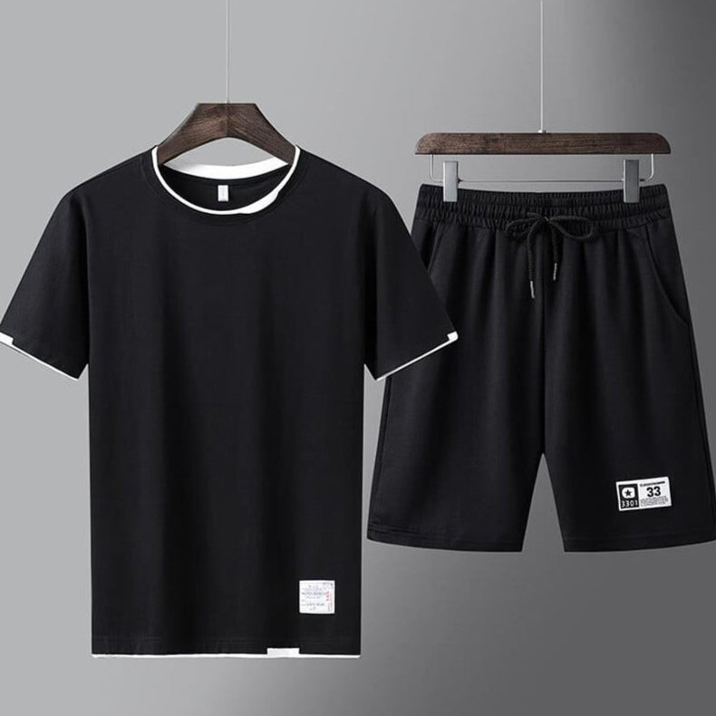 Completo sportivo nero da uomo, composto da maglietta e pantaloncini, appeso su grucce. Abbigliamento casual estivo, moda uomo, tessuto leggero.