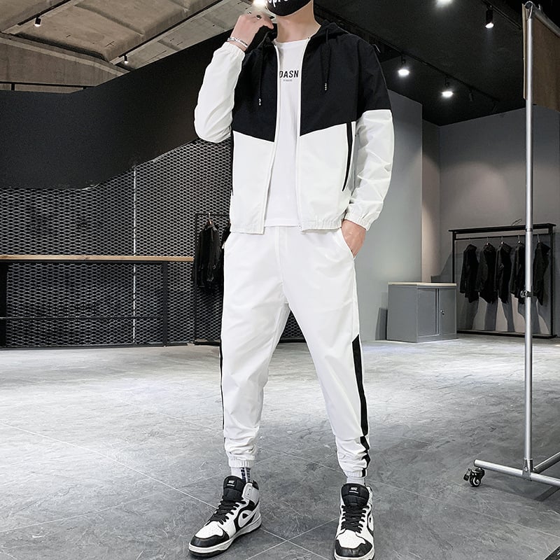 Uomo in tuta sportiva bianca e nera, scarpe da ginnastica, in un negozio di abbigliamento moderno. Stile casual, moda maschile, abbigliamento sportivo.