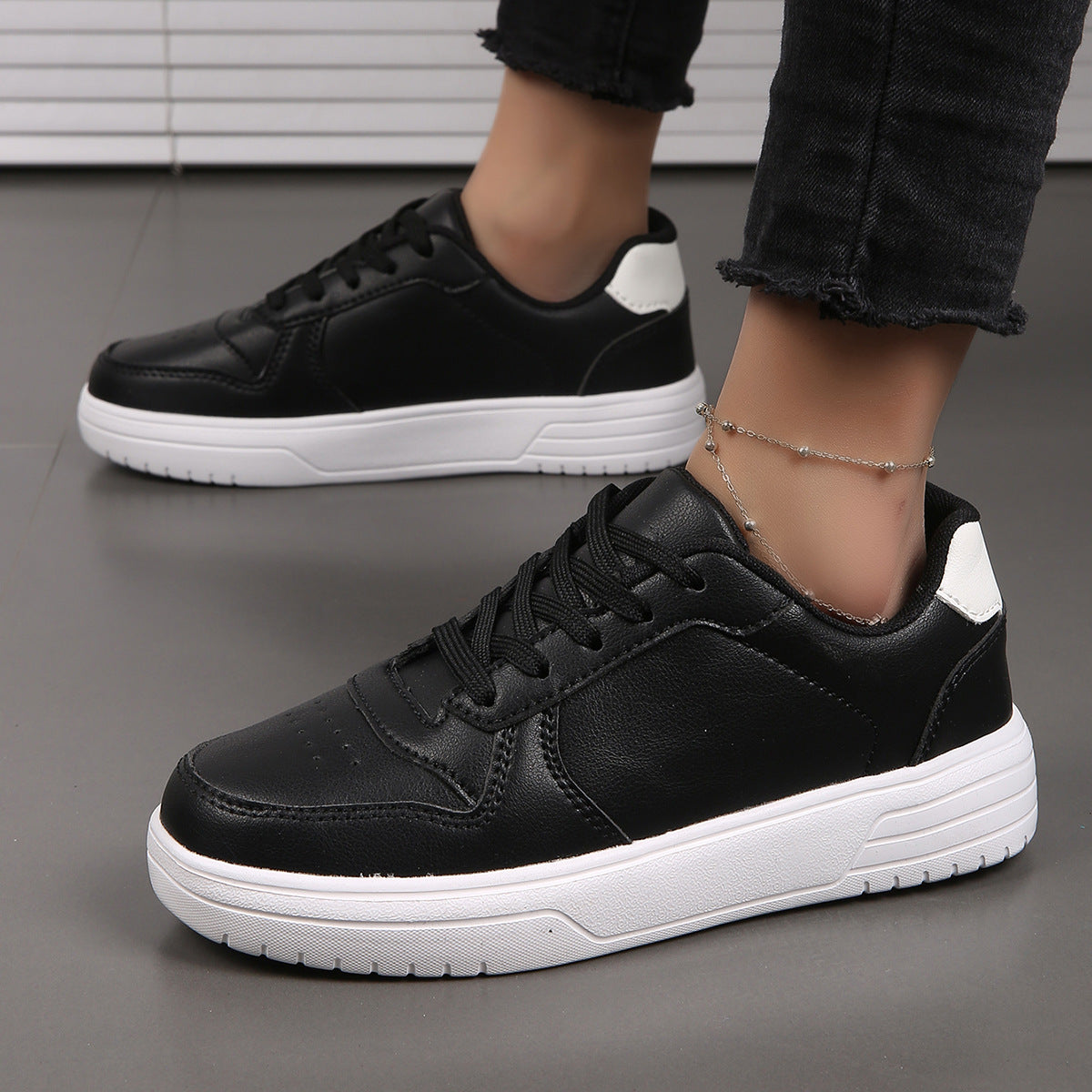 Scarpe da ginnastica nere da donna con suola bianca, indossate con jeans neri. Design moderno e casual, perfette per look quotidiani e sportivi.