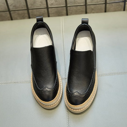 Scarpe slip-on nere in pelle con suola beige, design elegante e moderno, su sfondo grigio. Calzature moda uomo, stile casual e confortevole.