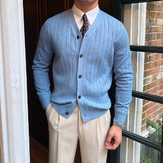 Uomo in cardigan azzurro a coste, camicia bianca e cravatta, pantaloni beige. Moda maschile elegante, abbigliamento autunnale, stile classico.