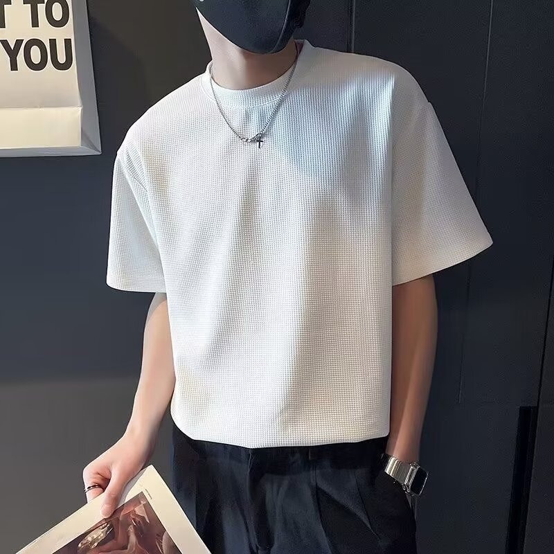 Uomo con maglietta bianca a maniche corte, collana e orologio, sfondo nero. Moda casual maschile, abbigliamento estivo elegante.