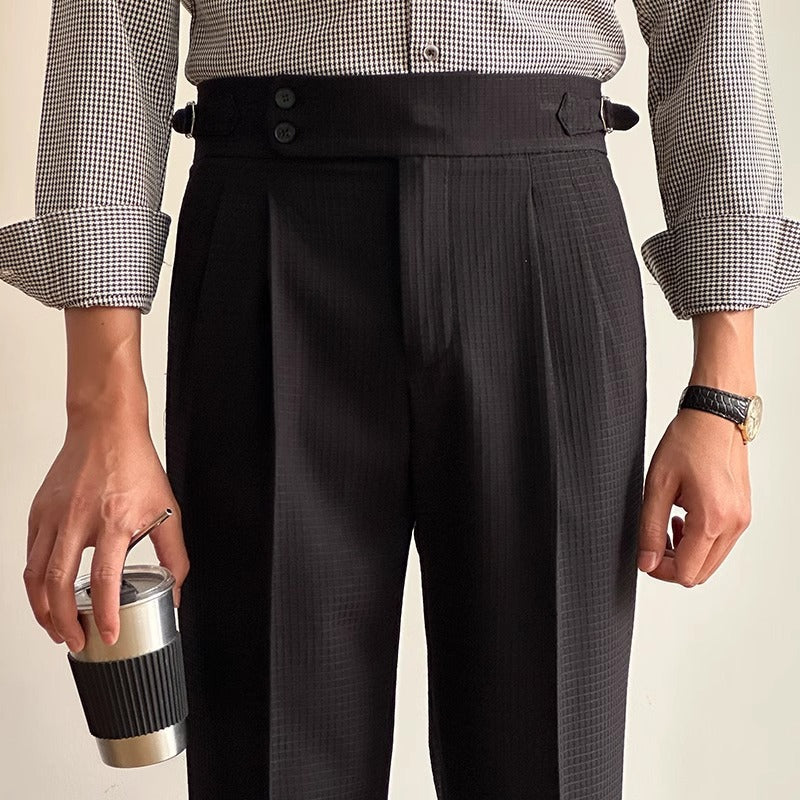 Uomo in camicia a quadri e pantaloni eleganti neri, tiene una tazza da caffè. Stile formale, moda maschile, accessori moderni.