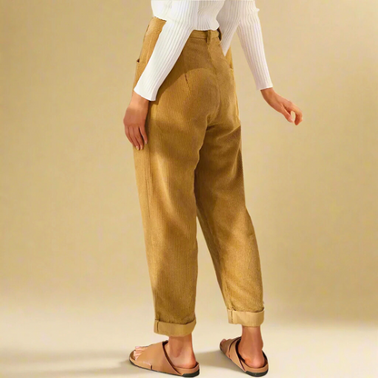 Donna in pantaloni a coste beige, maglia bianca a coste, sandali marroni. Moda casual, abbigliamento autunnale, stile rilassato.