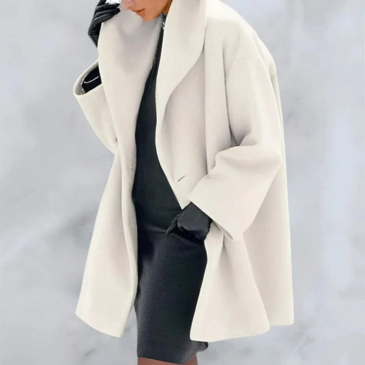 Donna con cappotto bianco elegante, abito nero e guanti in pelle. Moda invernale chic, stile sofisticato. Sfondo grigio chiaro.