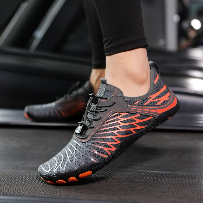 Scarpe da corsa minimaliste nere e arancioni su tapis roulant, design leggero e traspirante, ideali per allenamenti fitness e running.