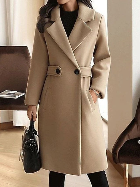 Cappotto beige elegante da donna, lungo, con bottoni neri e tasche, indossato con borsa nera. Perfetto per moda autunnale e invernale.