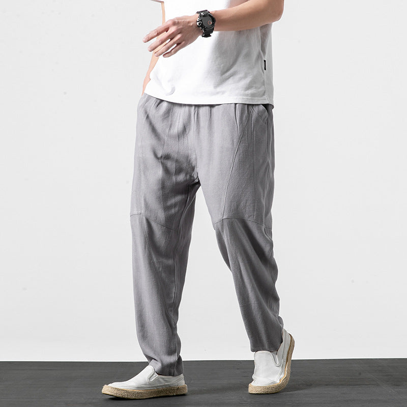 Uomo con pantaloni grigi larghi, t-shirt bianca e scarpe casual. Moda maschile, abbigliamento estivo, stile casual elegante.