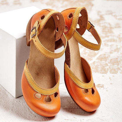 Scarpe da bambina in pelle arancione e gialla con cinturino, design vintage, su sfondo chiaro. Calzature eleganti per bambini, moda infantile.