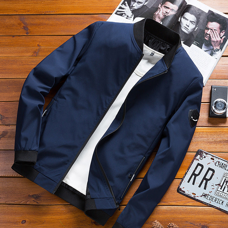 Giacca bomber blu scuro su tavolo di legno, con rivista e fotocamera vintage. Moda maschile, abbigliamento casual elegante.