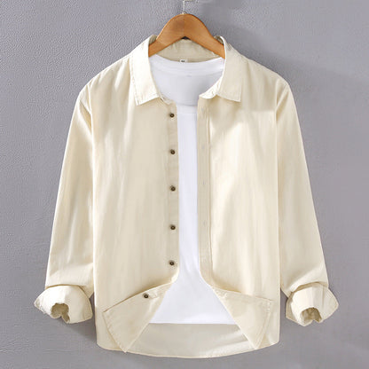 Camicia beige da uomo su gruccia, maniche lunghe, abbinata a t-shirt bianca. Moda casual, abbigliamento maschile elegante, sfondo grigio.