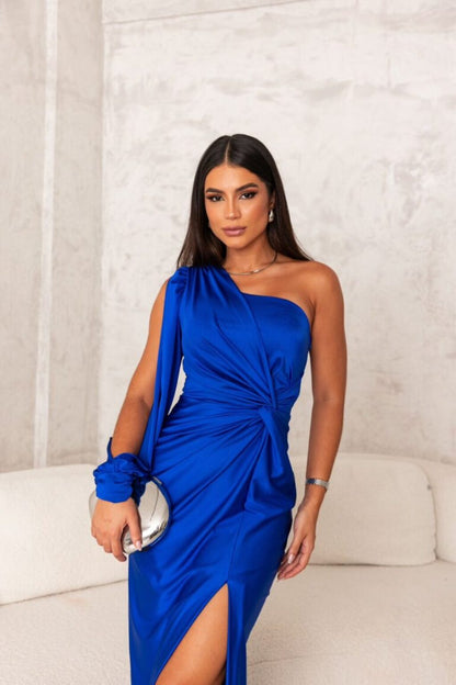 Donna in abito blu elegante monospalla, posa in un ambiente moderno. Moda femminile, abbigliamento da sera, stile sofisticato.