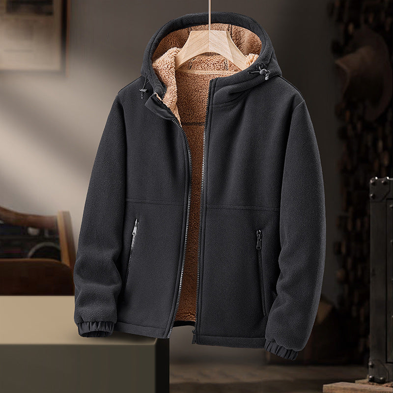 Giacca in pile nero con cappuccio, interno foderato in pelliccia sintetica marrone, chiusura zip, tasche laterali, appesa in ambiente interno.