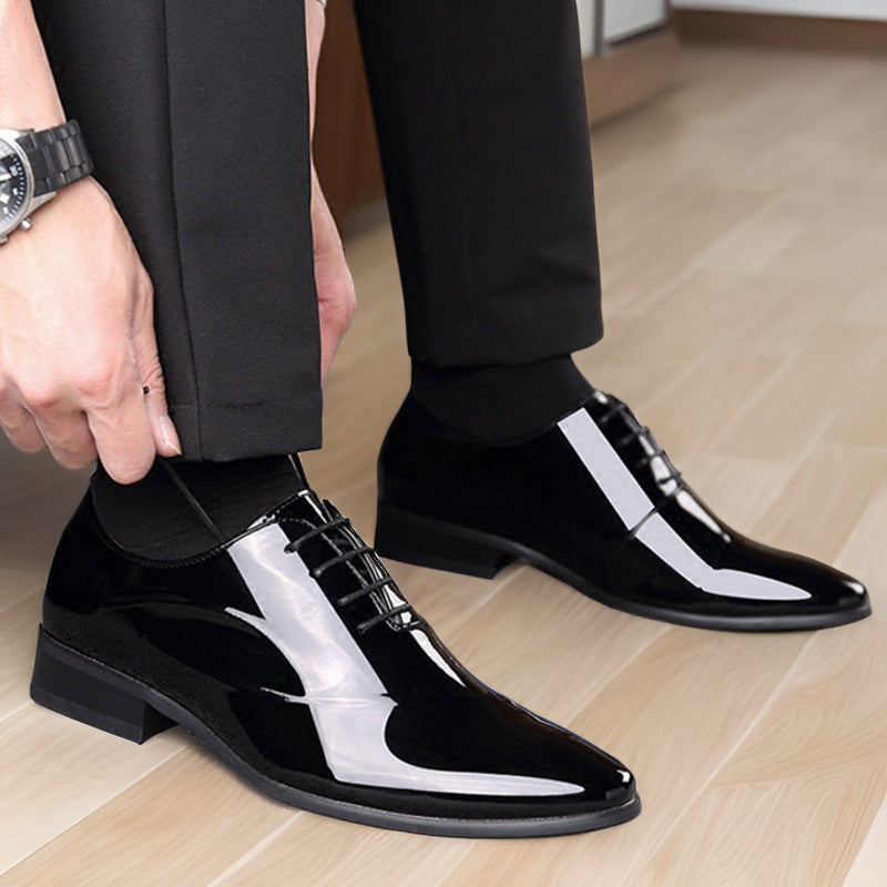Scarpe eleganti uomo in vernice nera, indossate con pantaloni neri su pavimento in legno chiaro. Scarpe formali lucide, moda maschile.