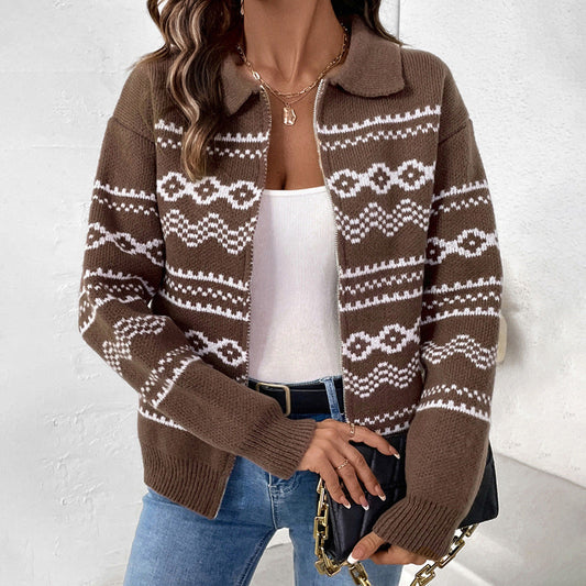 Donna con cardigan marrone a motivi geometrici bianchi, top bianco, jeans blu e borsa nera con catena dorata. Moda autunnale casual elegante.