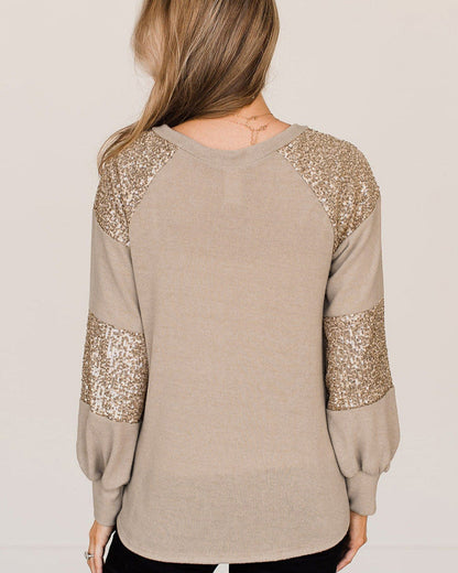 Donna di spalle indossa maglione beige con paillettes dorate su maniche e spalle, moda autunno inverno, abbigliamento casual elegante.
