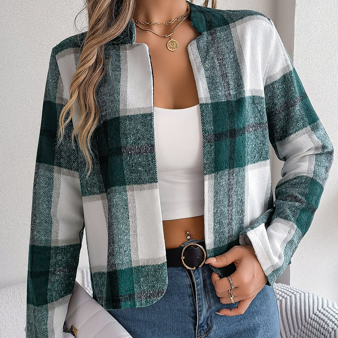 Donna con giacca a quadri verde e bianca, top bianco, jeans blu e borsa bianca. Moda autunnale casual, stile moderno e chic.