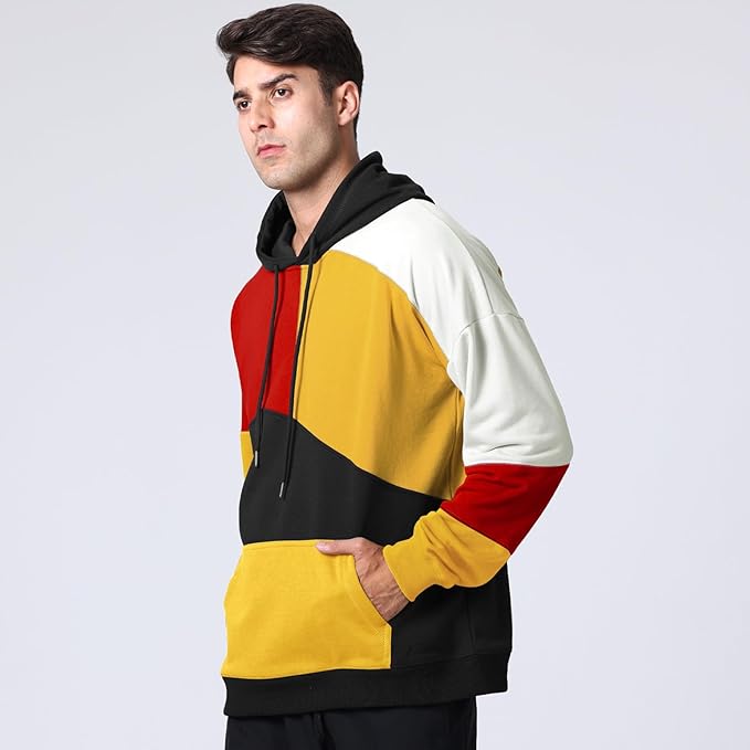 Uomo con felpa multicolore a blocchi di colore rosso, giallo, nero e bianco, sfondo grigio chiaro. Moda casual, abbigliamento moderno.