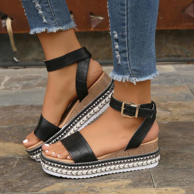 Sandali platform neri con cinturino alla caviglia, suola intrecciata, indossati con jeans strappati. Scarpe estive moda donna, tendenze calzature 2023.