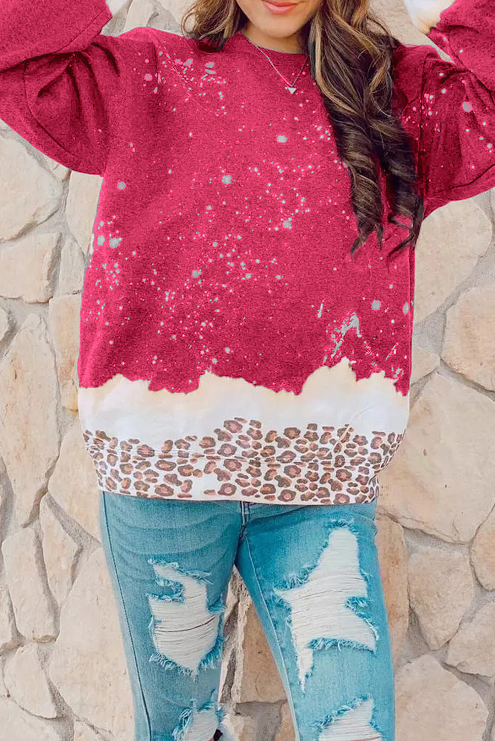 Maglione rosso con motivo a spruzzi bianchi e bordo leopardato, indossato con jeans strappati. Moda casual donna, abbigliamento autunnale trendy.