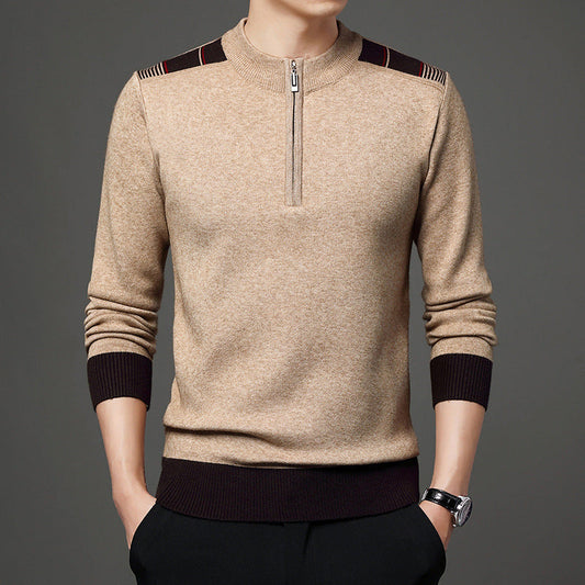 Maglione beige da uomo con zip corta, dettagli marroni su spalle e polsini, indossato su sfondo grigio. Moda maschile elegante e casual.