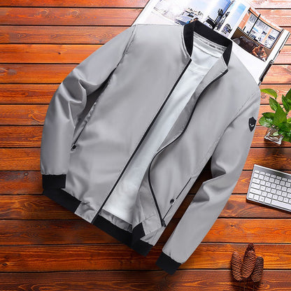 Giacca bomber grigia su tavolo in legno, con zip nera e dettagli a contrasto. Moda uomo, abbigliamento casual, stile moderno.