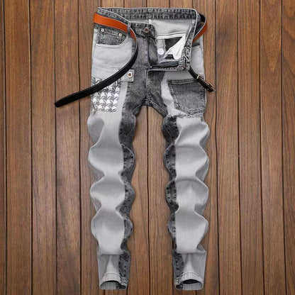 Jeans slim fit da uomo in denim grigio con dettagli a contrasto, cintura in pelle marrone, su pavimento in legno. Moda casual maschile.