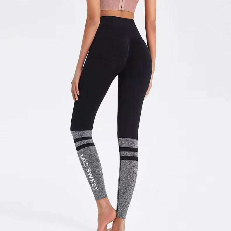 Donna in leggings sportivi neri e grigi con scritta "MISS SWEET", top rosa, posa di schiena. Abbigliamento fitness, moda activewear.