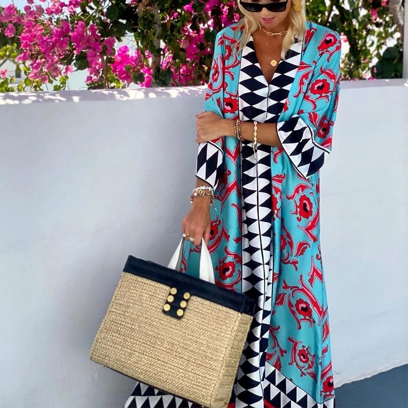 Donna con abito lungo a motivi geometrici e floreali, borsa di paglia, sfondo di fiori rosa. Moda estiva, stile elegante, accessori di tendenza.