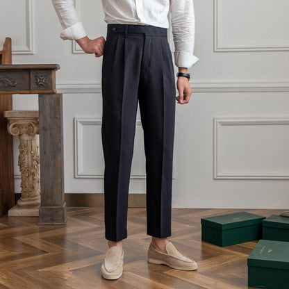 Pantaloni eleganti uomo neri, abbinati a camicia bianca e mocassini beige, su pavimento in legno. Stile classico, moda maschile formale.