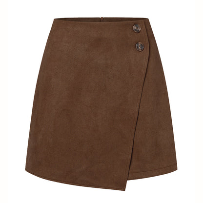 Gonna corta marrone in pelle scamosciata con design a portafoglio e due bottoni decorativi. Moda donna, abbigliamento autunnale elegante.