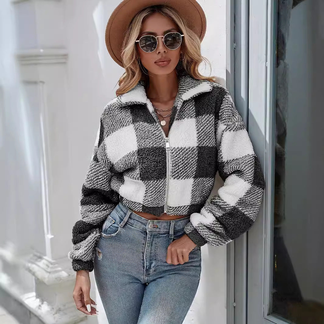 Donna con giacca a quadri bianca e nera, jeans attillati, cappello marrone e occhiali da sole. Moda autunnale, stile casual chic.