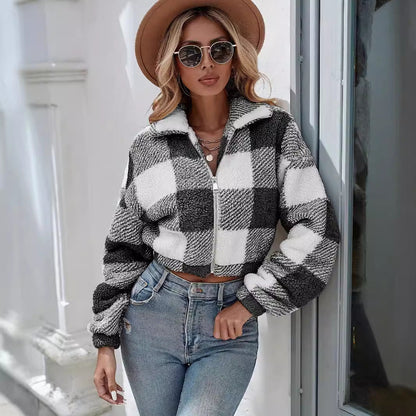 Donna con giacca a quadri bianca e nera, jeans attillati, cappello marrone e occhiali da sole. Moda autunnale, stile casual chic.