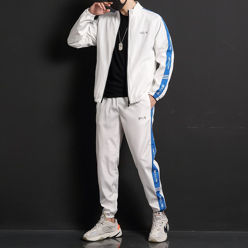 Tuta sportiva bianca con strisce blu, indossata da uomo su sfondo nero. Abbigliamento casual, moda maschile, stile urbano.