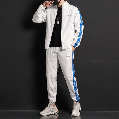 Tuta sportiva bianca con strisce blu, indossata da uomo su sfondo nero. Abbigliamento casual, moda maschile, stile urbano.