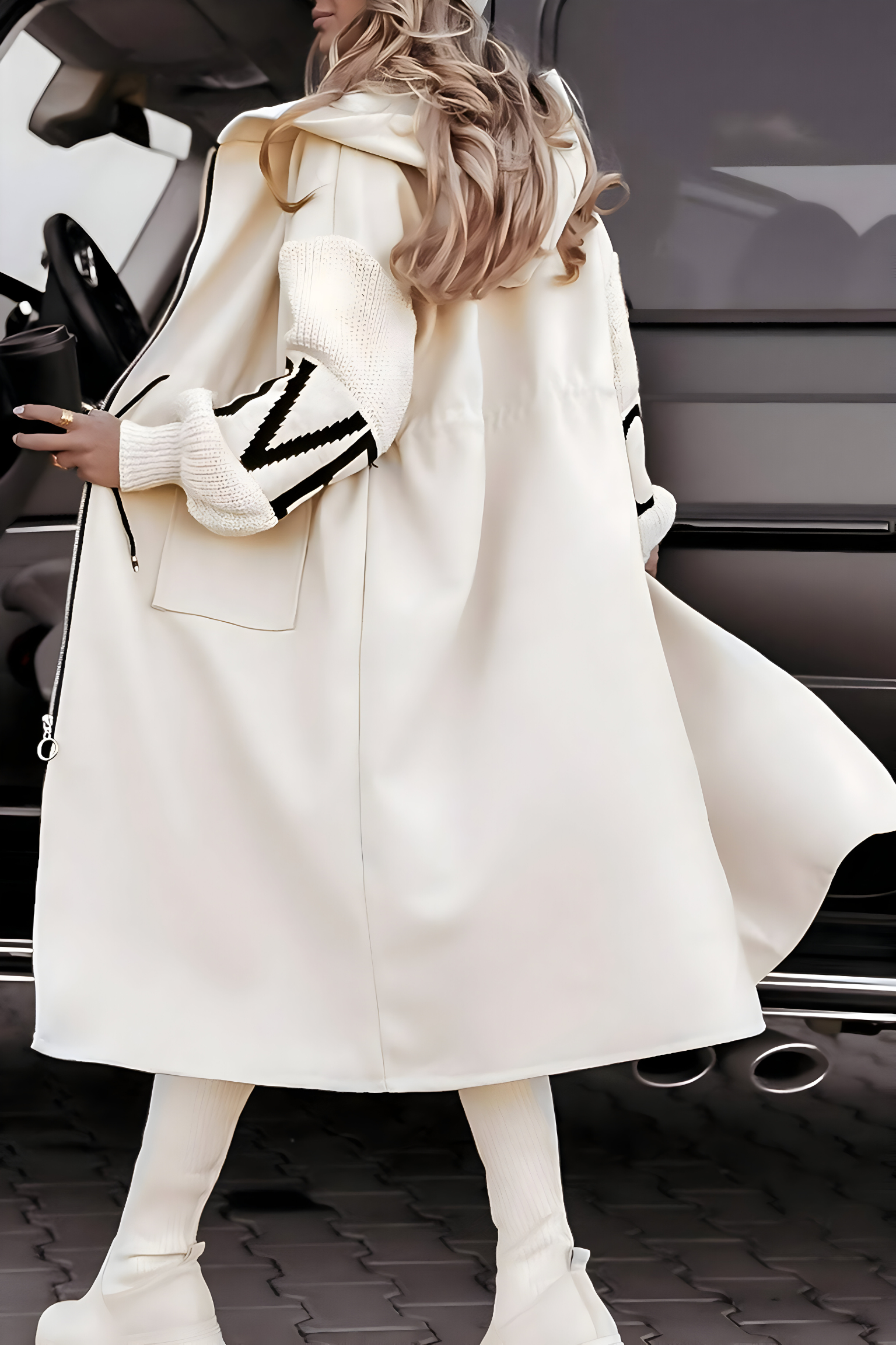 Donna con cappotto bianco elegante, stivali alti e capelli lunghi, accanto a un SUV grigio. Moda invernale, stile urbano, tendenze 2023.