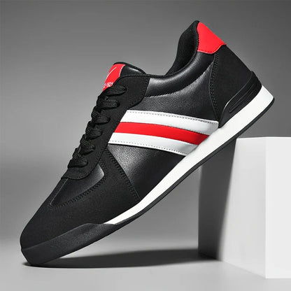 Scarpa sportiva nera con strisce rosse e bianche, suola bianca, design moderno, posizionata su un cubo bianco. Scarpe da ginnastica eleganti uomo.