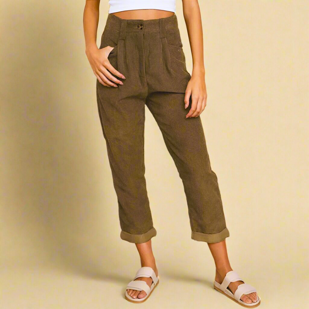 Pantaloni marroni a vita alta in velluto a coste, indossati con sandali bianchi e top bianco. Moda casual donna, abbigliamento autunnale.