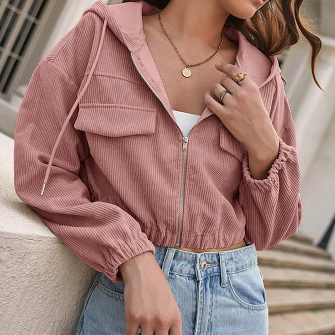 Donna con giacca a vento rosa, jeans a vita alta, collana e anelli. Moda casual femminile, abbigliamento autunnale, stile urbano chic.