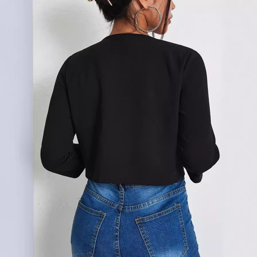 Donna di spalle con giacca nera e jeans blu, orecchini a cerchio grandi. Moda casual femminile, abbigliamento trendy, stile urbano.