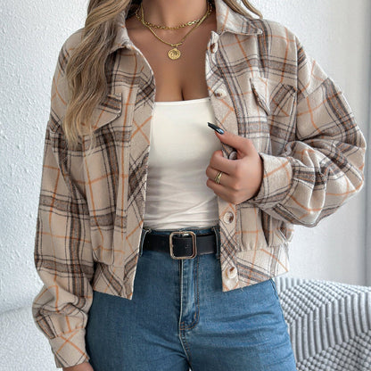 Donna con camicia a quadri beige e marrone, top bianco, jeans a vita alta, collana dorata. Moda autunnale casual, stile urbano femminile.