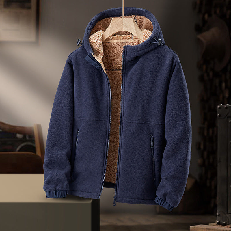 Giacca in pile blu con cappuccio, interno foderato in pelliccia sintetica beige, appesa su gruccia in ambiente rustico. Abbigliamento invernale caldo.